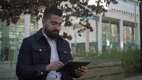 Bearded-man-using-digital-tablet-on-street